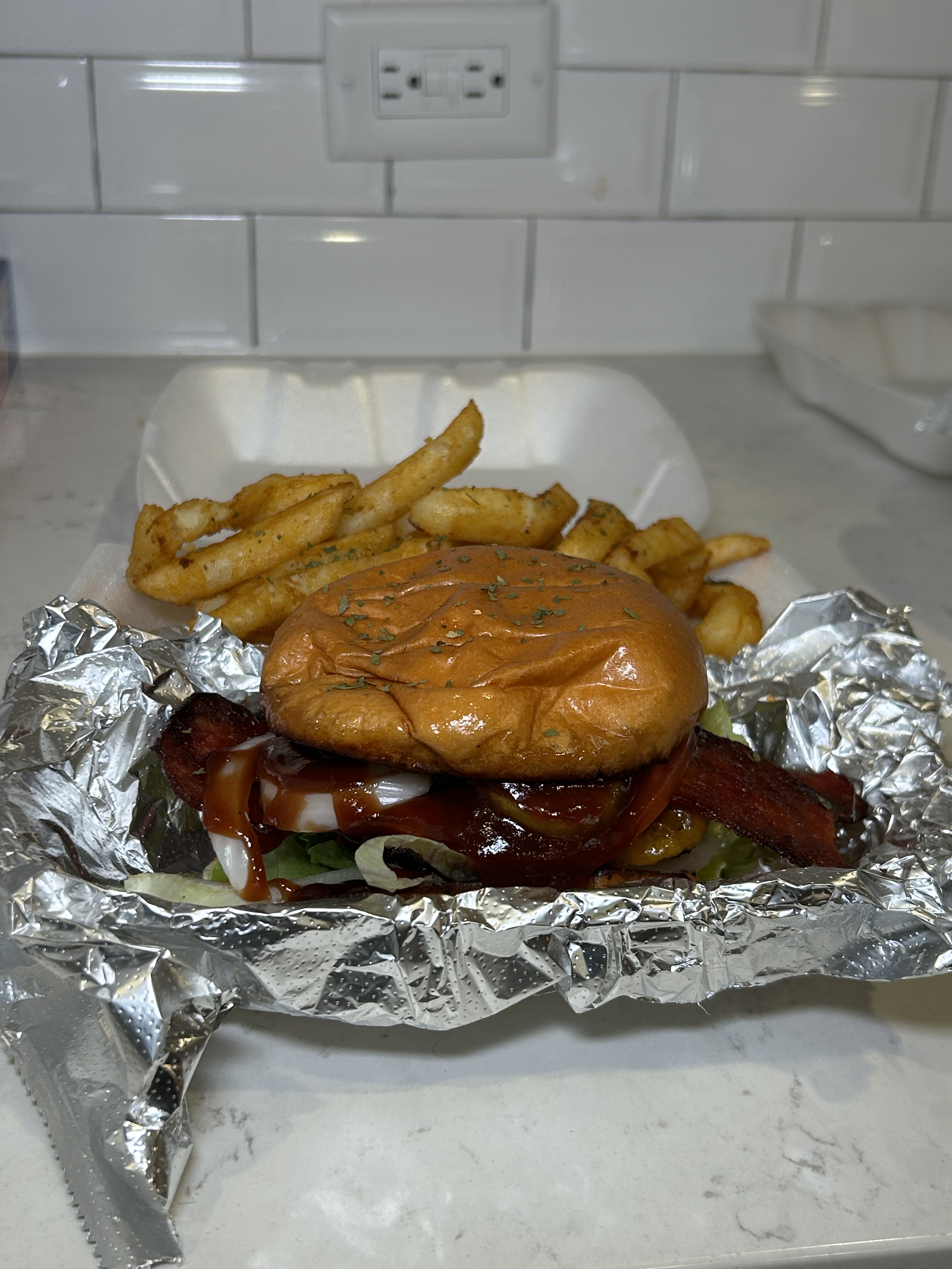 Side view of a BBQ Addiction Burger with fries